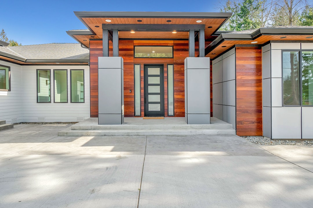A crisp 'For Sale' sign stands on the manicured lawn in front of a beautiful, modern home, illustrating the core subject of real estate transactions.