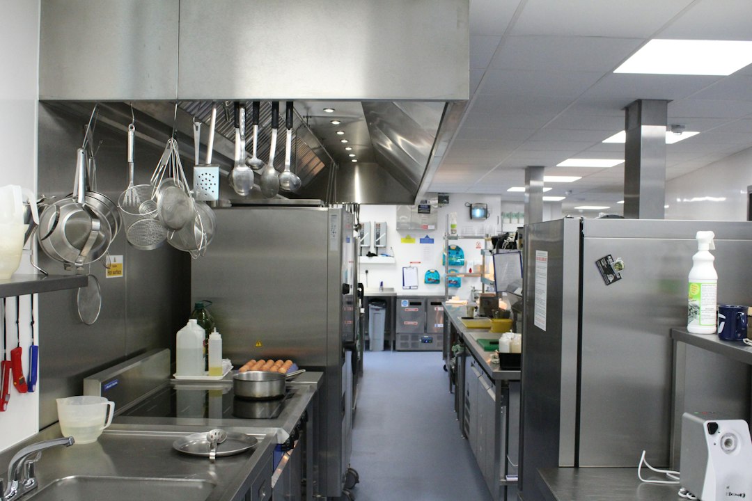 A chef in a clean, professional stainless steel kitchen meticulously preparing a dish, highlighting the behind-the-scenes reality of food preparation.