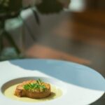 Close-up of a beautifully plated gourmet meal on a dark plate, representing an expensive dinner at a high-end restaurant.