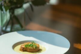 Close-up of a beautifully plated gourmet meal on a dark plate, representing an expensive dinner at a high-end restaurant.