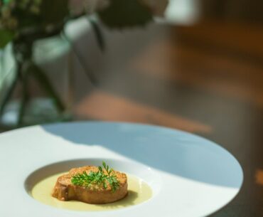 Close-up of a beautifully plated gourmet meal on a dark plate, representing an expensive dinner at a high-end restaurant.